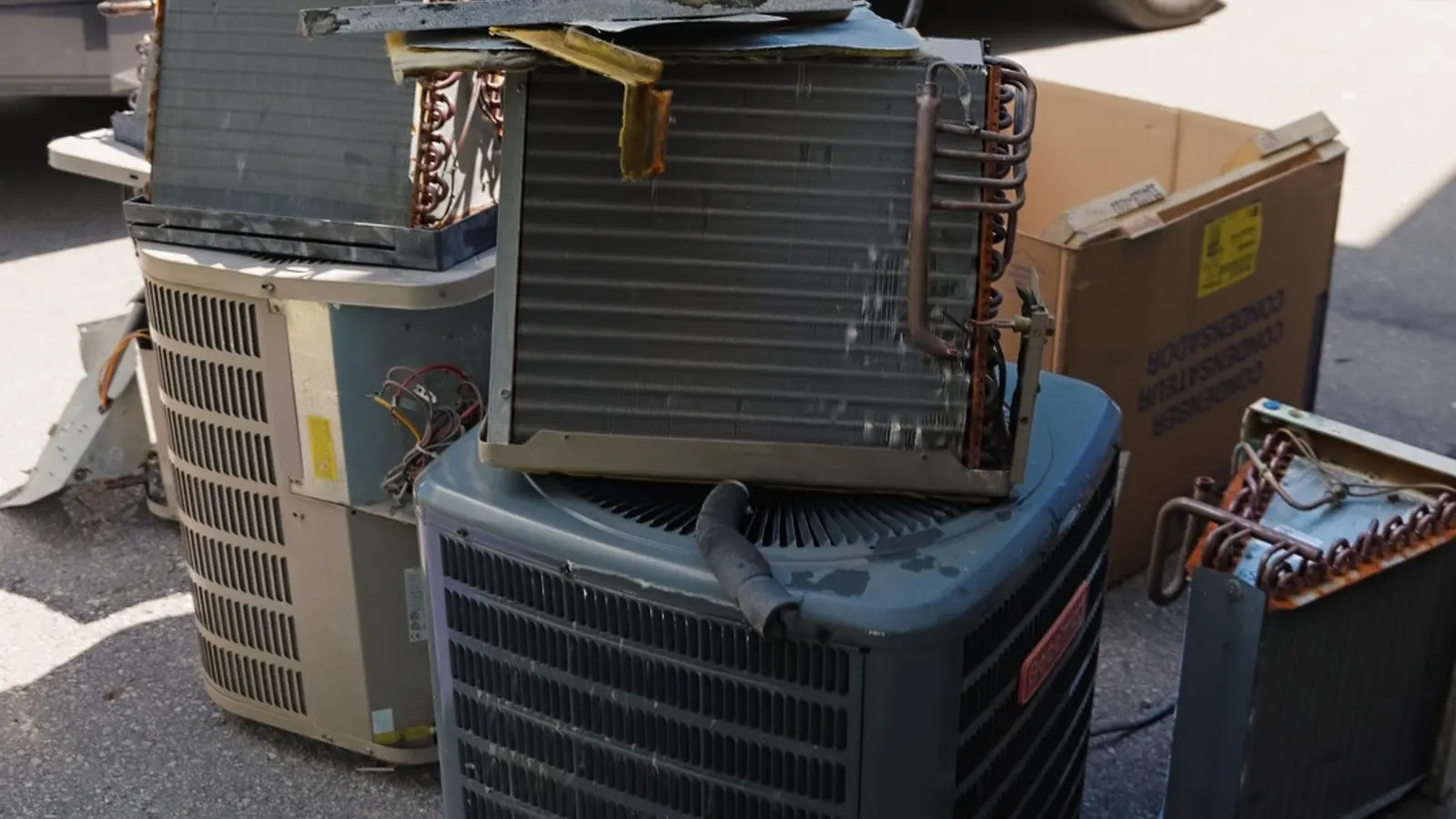 Old air conditioners and coils removed and stacked for disposal