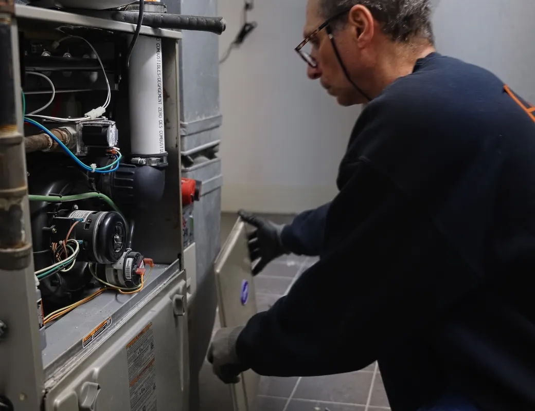 H&C technician servicing a gas furnace burner assembly